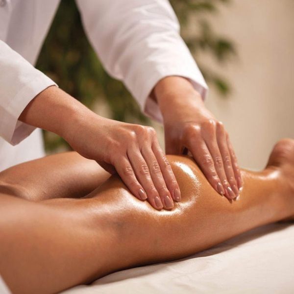 Therapist giving a full body massage to a client's leg